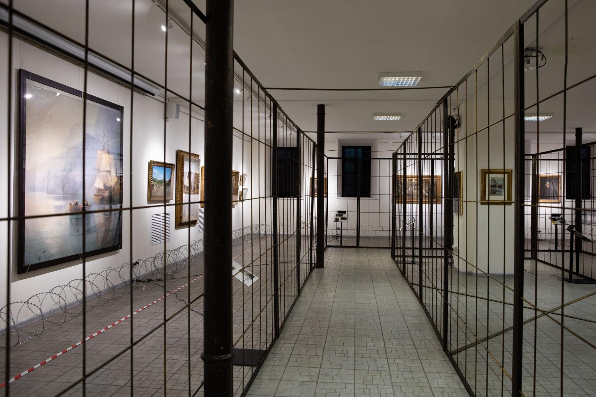 Картини на виставці Порошенка символічно вирішили оточити ґратами та колючим дротом.